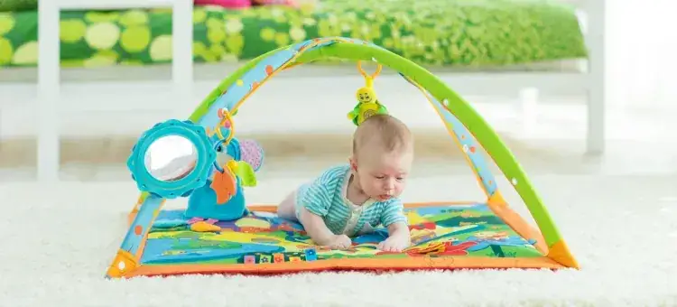 niemowlę na macie edukacyjnej bawi się zabawkami