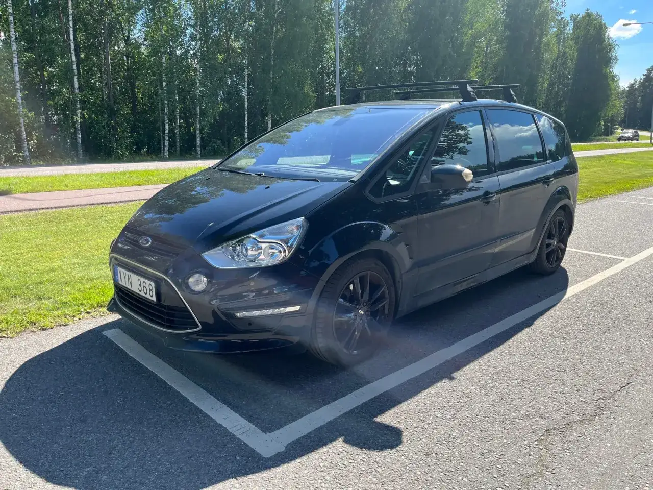 Svart Ford S-Max med takr&auml;cke parkerad. En liten skada syns vid fr&auml;mre st&ouml;tf&aring;ngaren, ett potentiellt Ford S-Max problem.