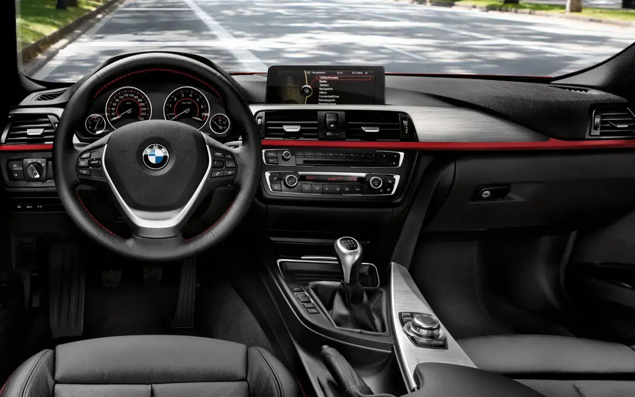 Wnętrze BMW F30 M Pakiet: kierownica, deska rozdzielcza z ekranem multimediów i panelem klimatyzacji, dźwignia zmiany biegów.