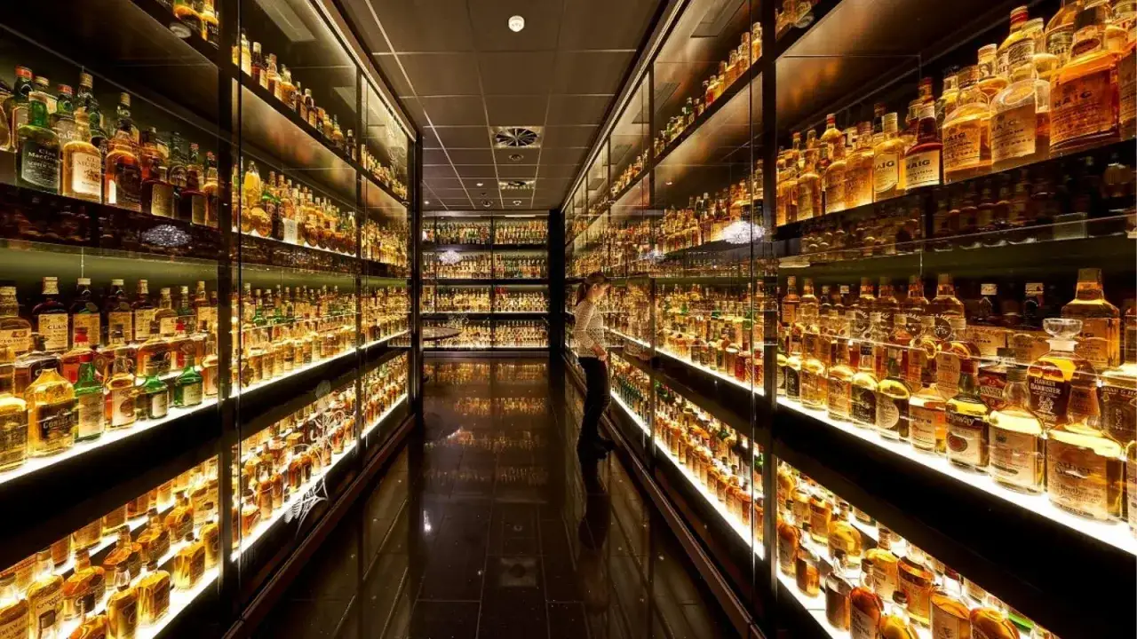 En kvinna beundrar en enorm samling whiskyflaskor i en upplyst monter, en dr&ouml;m f&ouml;r alla som &auml;lskar whiskyprovning i Edinburgh.
