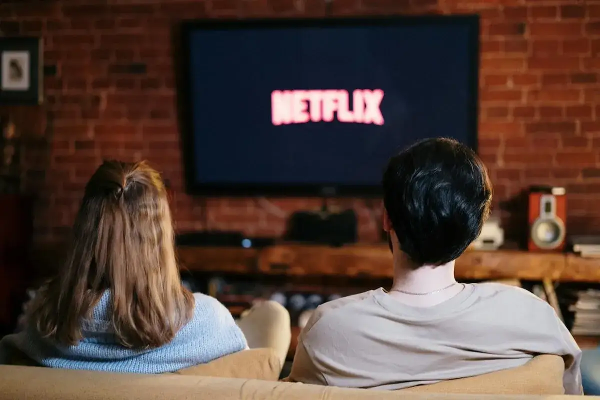 Coppia sul divano, schermo Netflix acceso. Serata perfetta per scoprire nuove serie tv da vedere.