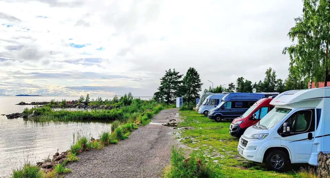 Husbilarna st&aring;r uppradade vid vattnet p&aring; spiken camping. En vacker utsikt &ouml;ver sj&ouml;n och molnen.