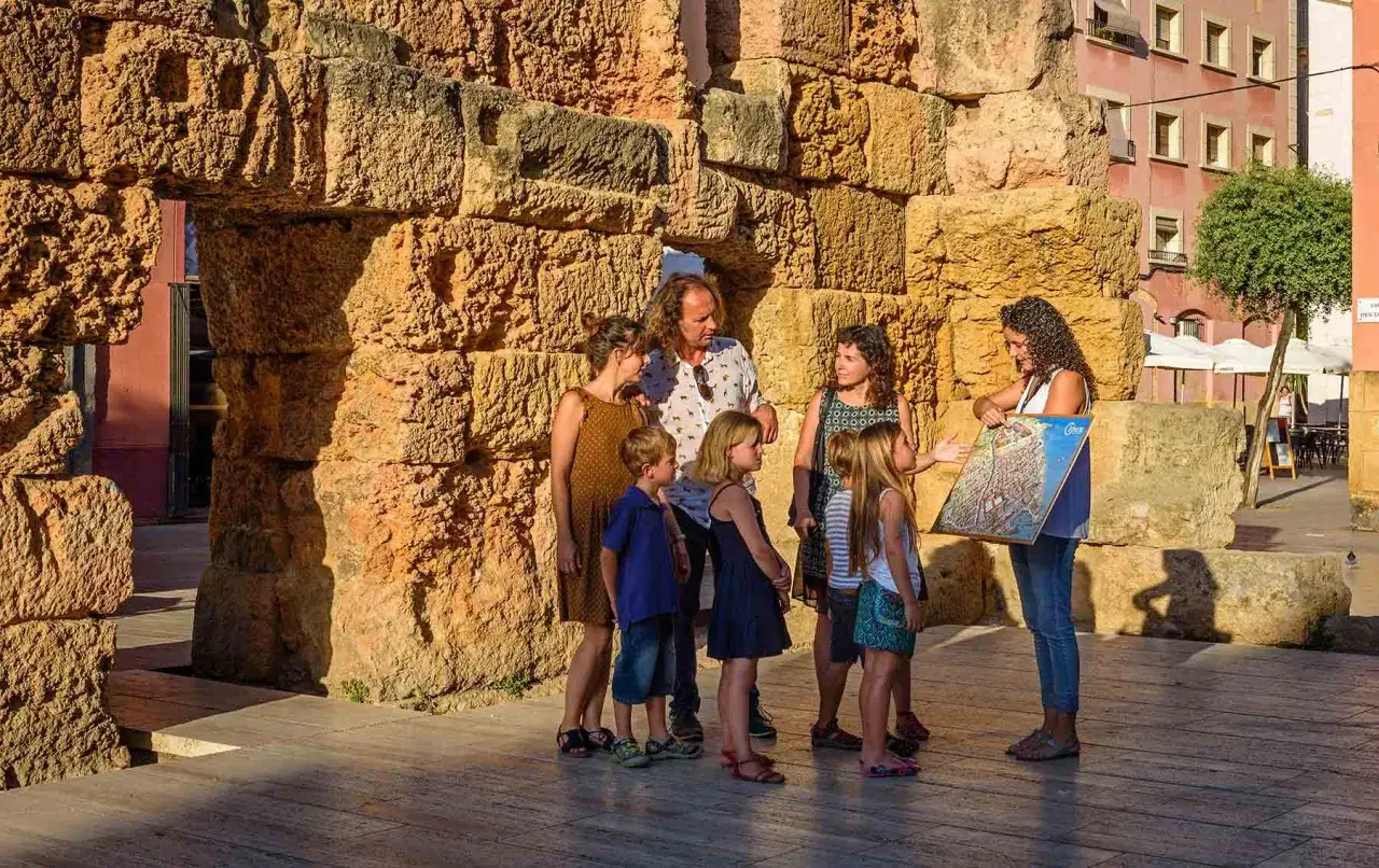 Familia explorando ruinas romanas en Tarragona con niños, aprendiendo sobre la historia.