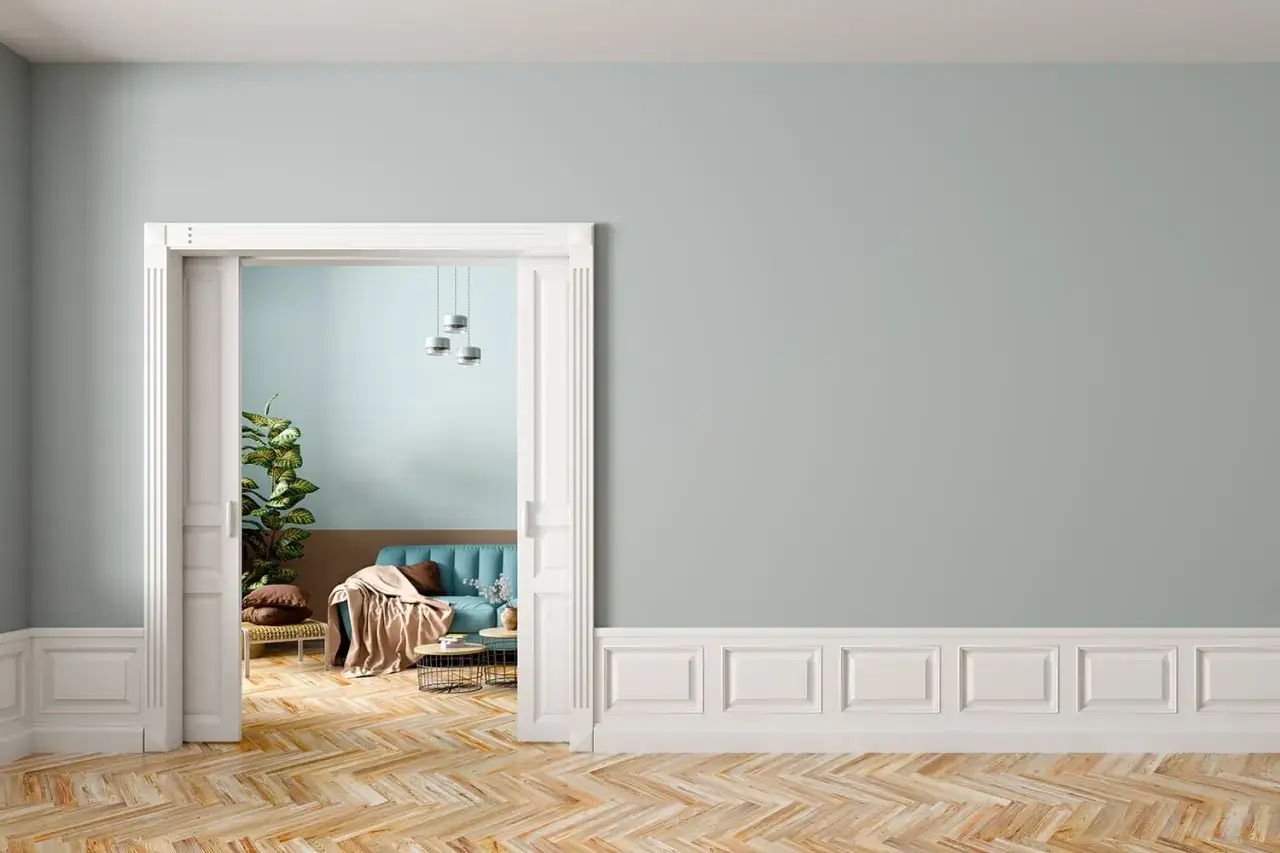 Un elegante soggiorno con divano blu e parquet a spina di pesce. Le pareti sono dipinte in tonalit&agrave; pastello, con un pannello in cartongesso effetto legno che aggiunge un tocco di calore.