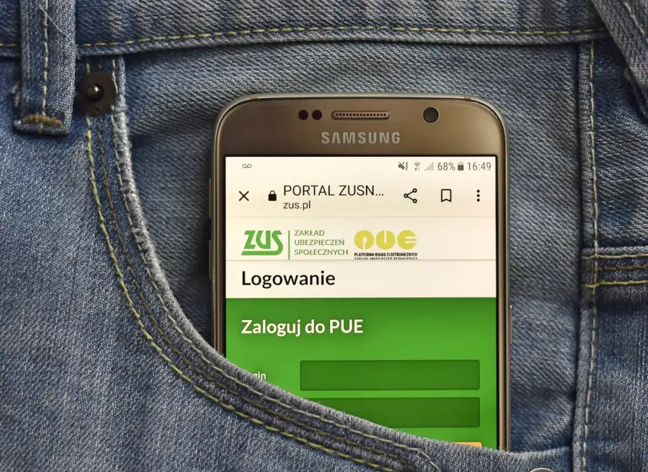 Telefon w kieszeni dżinsów wyświetla stronę logowania do PUE ZUS. Dowiedz się, jak założyć PUE ZUS.