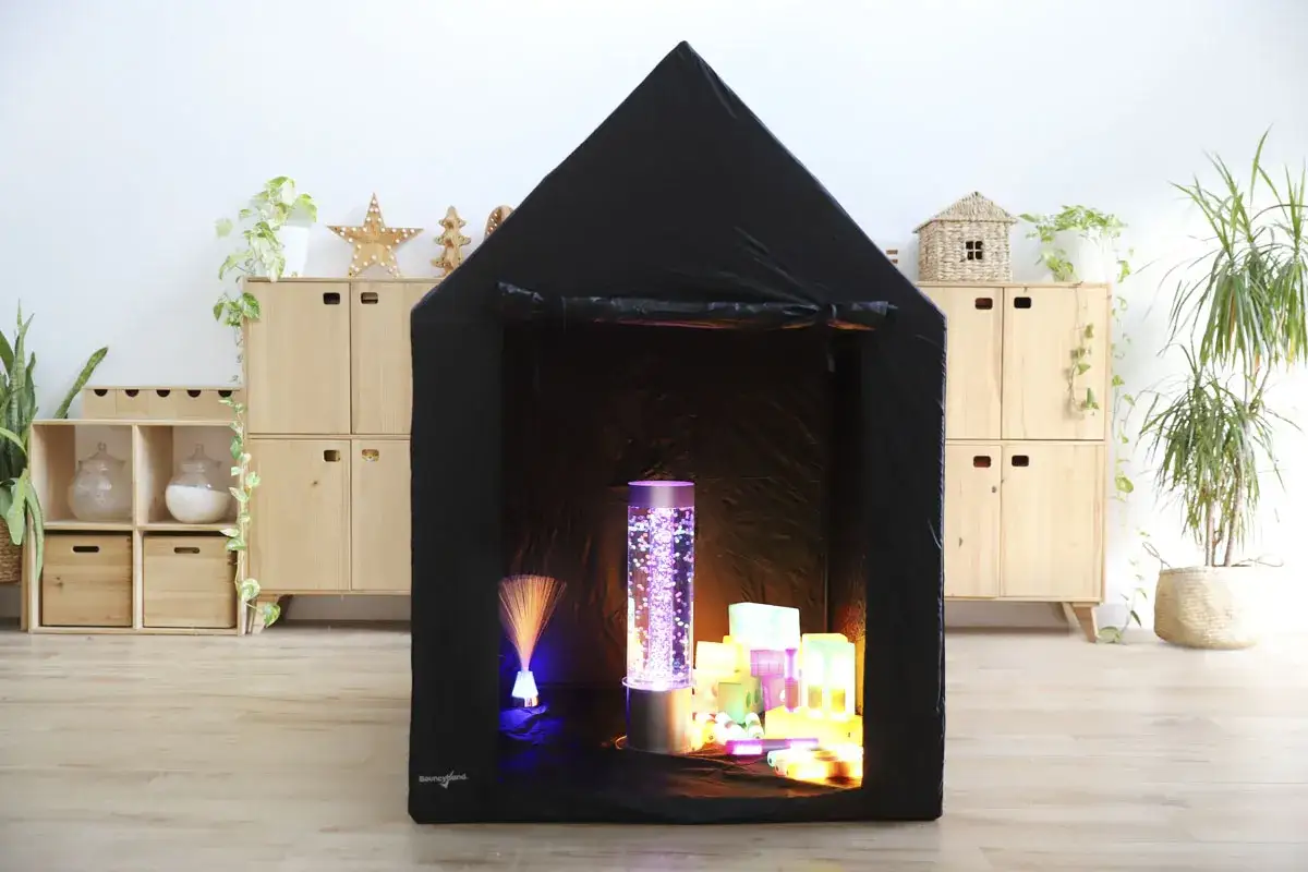 Tienda negra con luces de burbujas y cubos luminosos, creando un aula multisensorial infantil mágica.