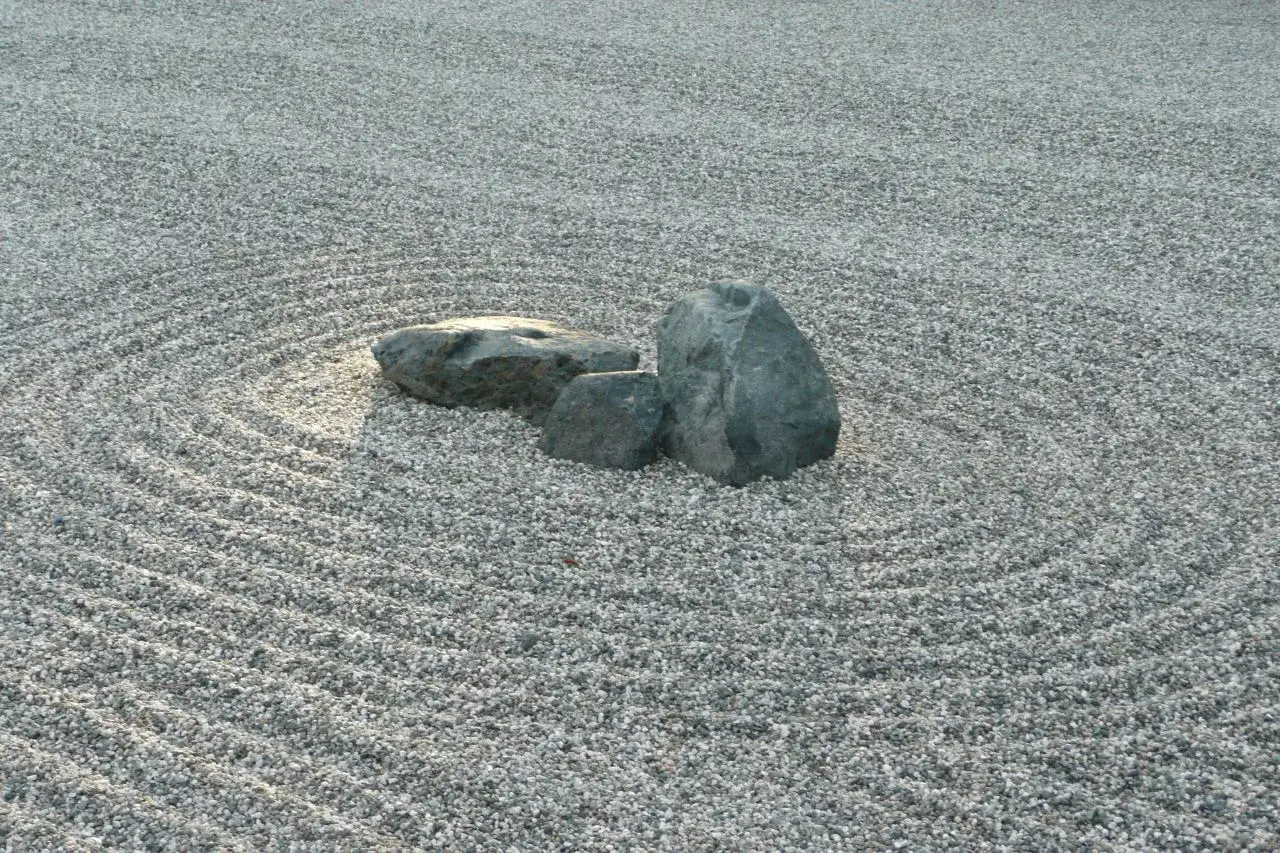 Un jardín zen japonés con rocas sobre grava rastrillada en círculos concéntricos, evocando serenidad y contemplación.