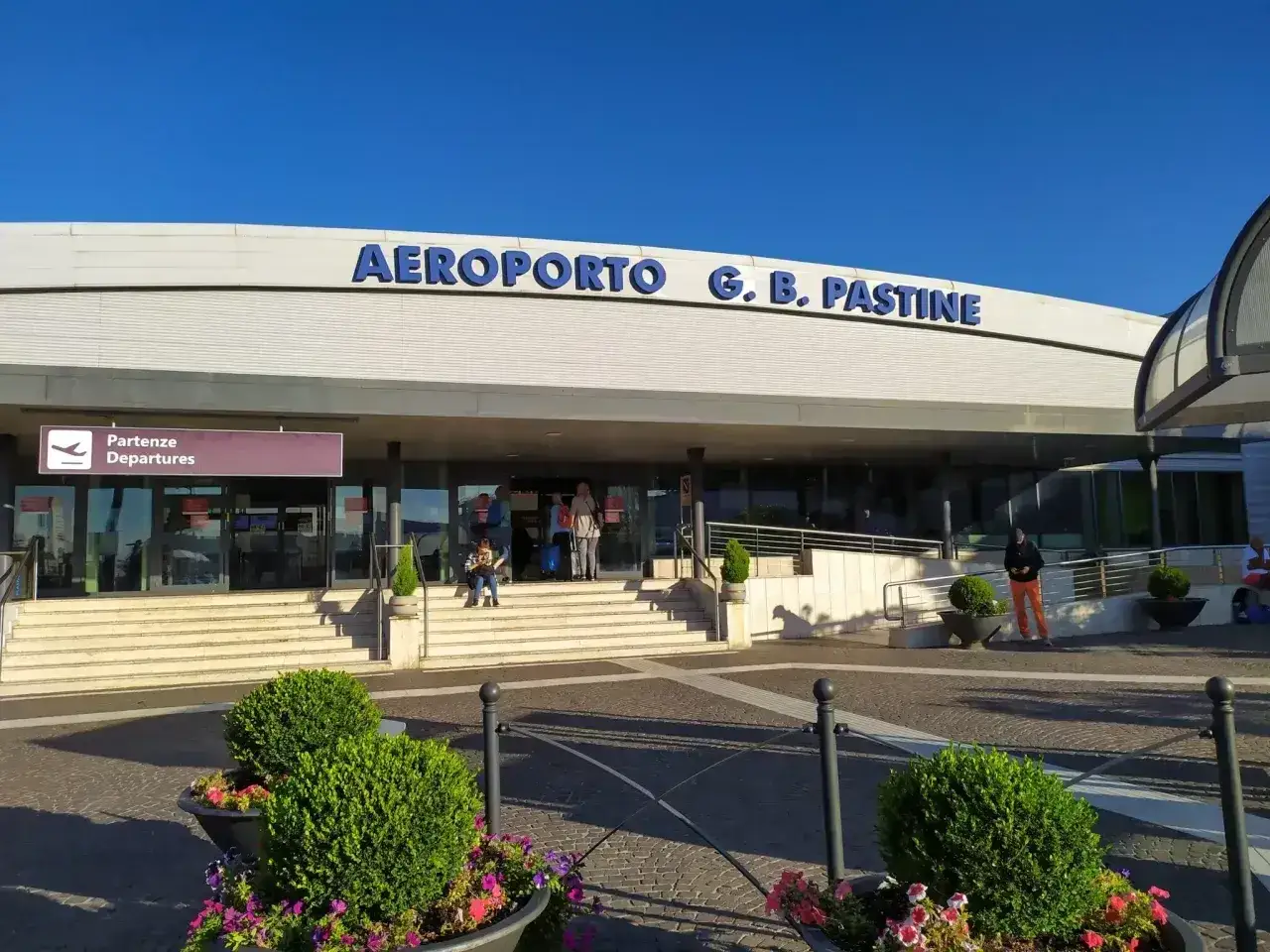 Wejście do Aeroportu G. B. Pastine, Rzym Ciampino. Ludzie czekają na odloty.