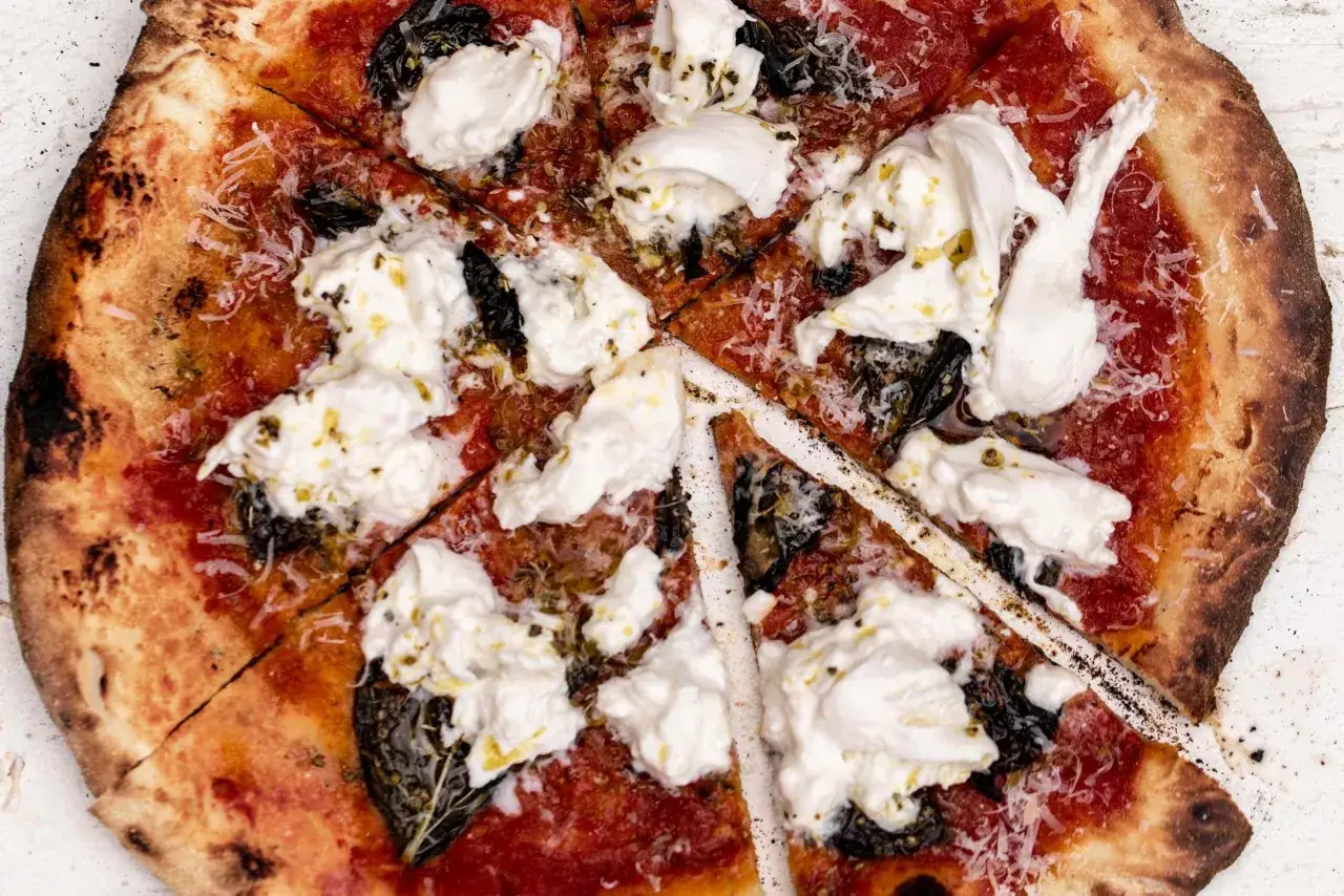 Une délicieuse pizza burrata, garnie de sauce tomate, de fromage crémeux et d'herbes fraîches, prête à être dégustée.