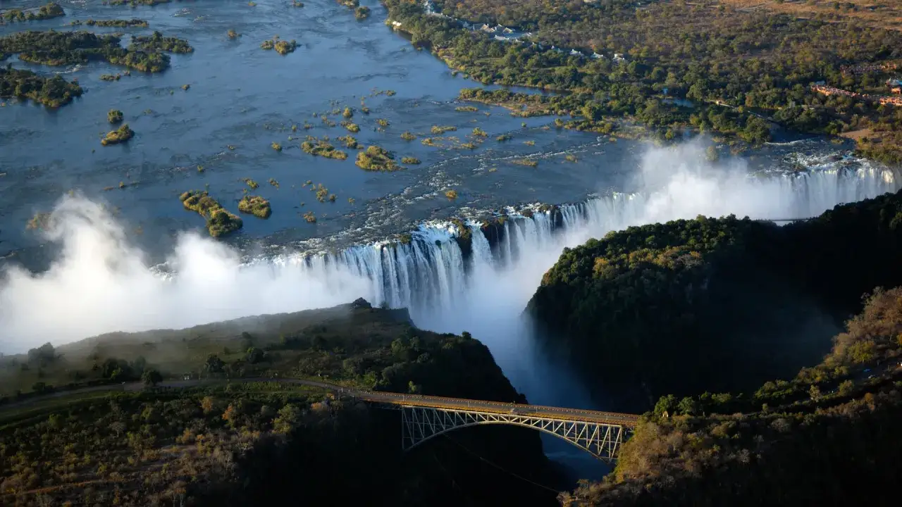 Spektakularne Wodospady Wiktorii, idealne na wycieczkę do Zimbabwe. Most nad kanionem, mgła wodna i bujna roślinność.