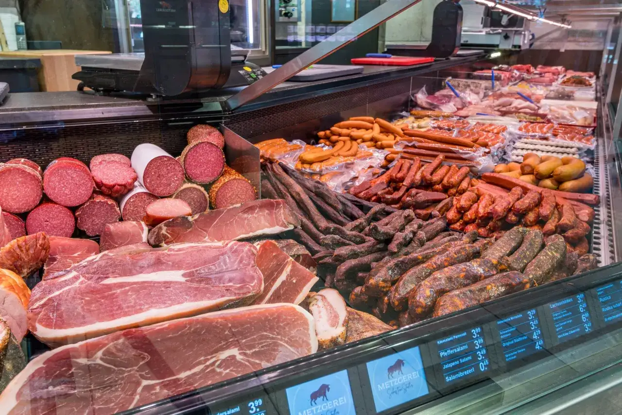 Reichhaltige Auswahl an bayerischer Wurst und Schinken in einer Metzgerauslage.