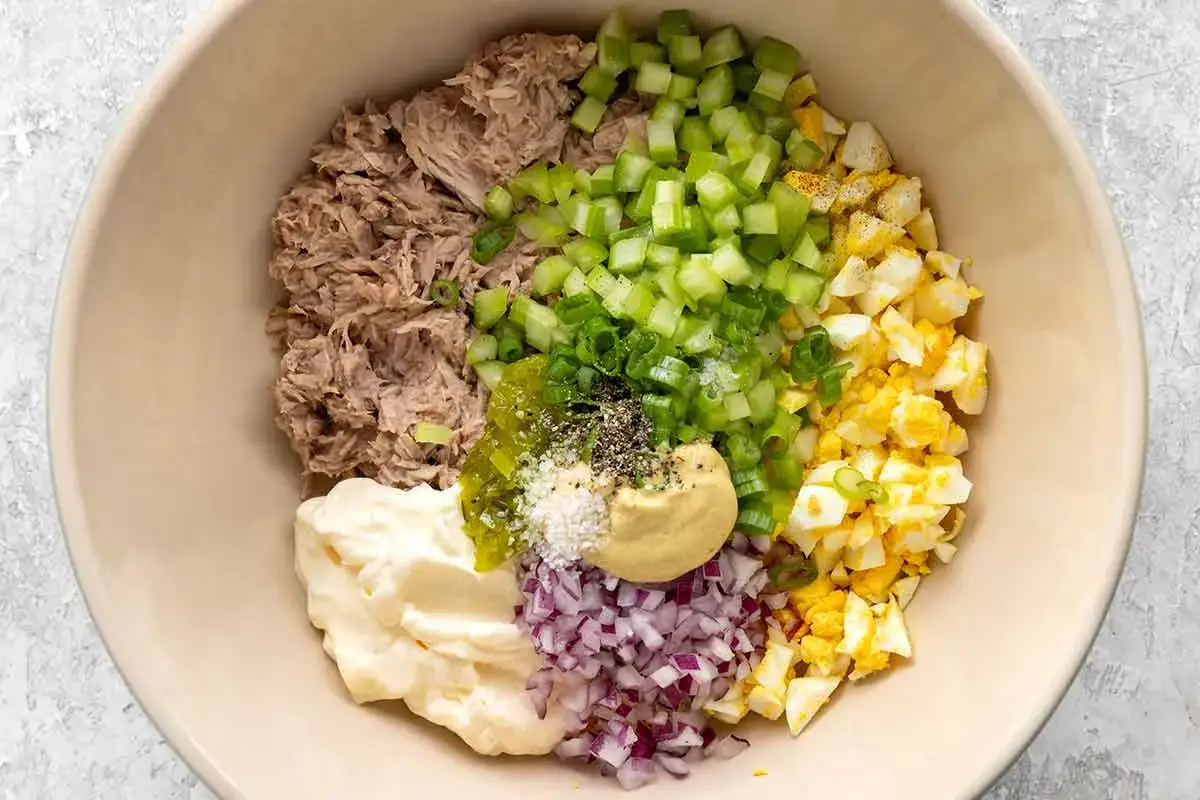 Zutaten für ein klassisches Thunfischsalat Rezept: Thunfisch, Mayonnaise, Sellerie, Ei, rote Zwiebeln, Senf und Gewürze.