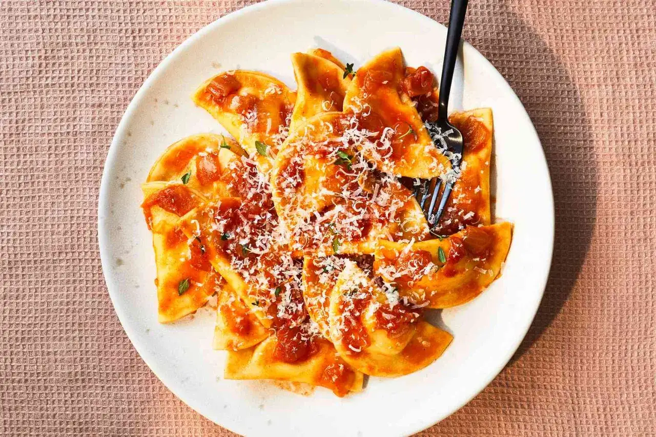 Pyszne ravioli z sosem pomidorowym i startą mozzarellą, posypane świeżymi ziołami. Idealne danie dla miłośników włoskich smaków.