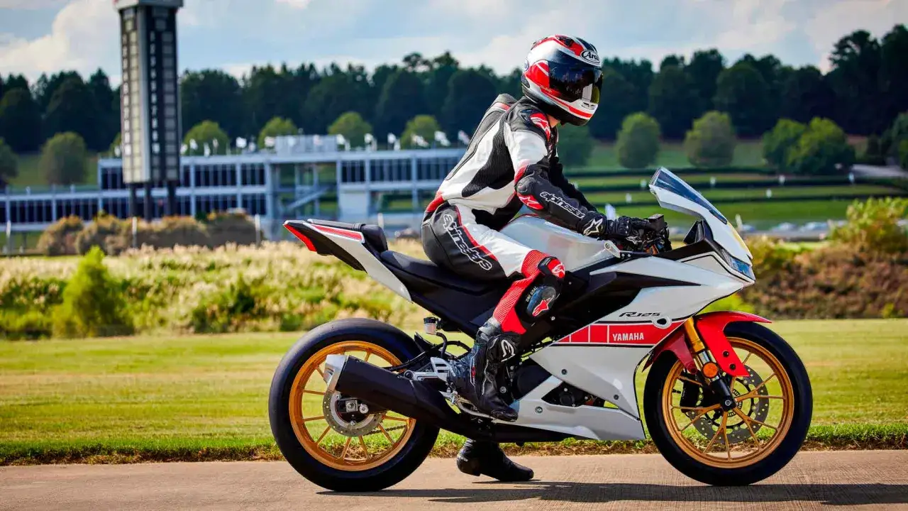 Piloto con traje de carreras en una Yamaha R125 blanca y roja, lista para alcanzar su **yamaha r125 top speed** en una pista.