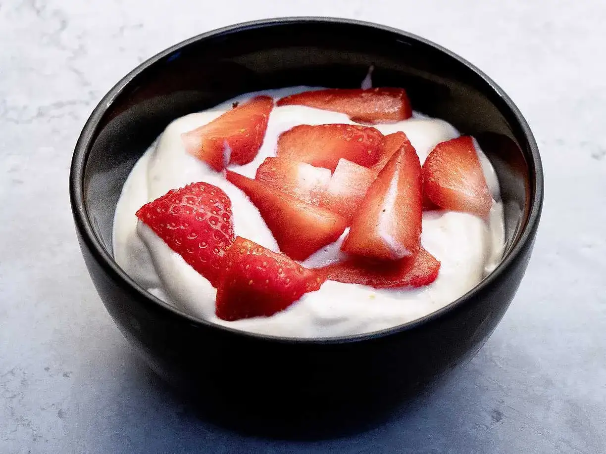 En sk&aring;l med kr&auml;mig hemmagjord glass toppad med f&auml;rska jordgubbsbitar. En perfekt sommardessert.