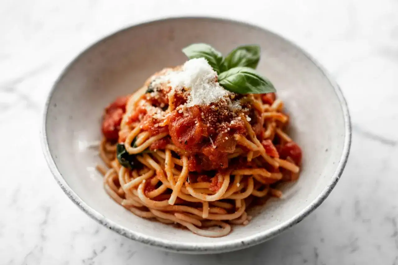 Ein Teller Spaghetti Napoli mit Tomatensauce, Basilikum und Parmesan.