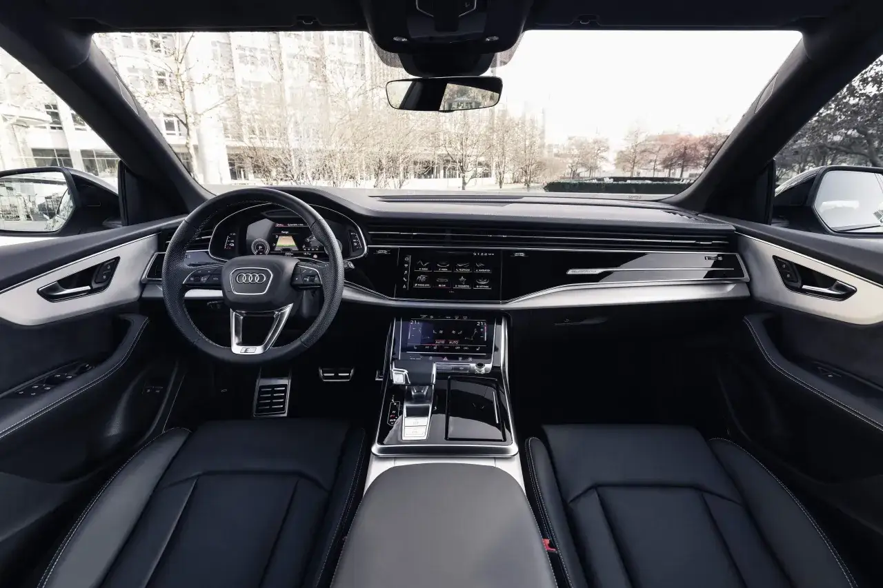 Interni lussuosi dell'Audi Q8 con cruscotto digitale, volante sportivo e sedili in pelle nera.