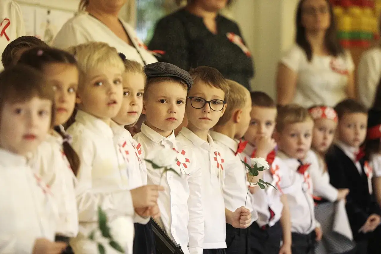 Dzieci w białych koszulach z kotylionami w barwach narodowych, trzymające białe róże. To piękna definicja patriotyzmu.