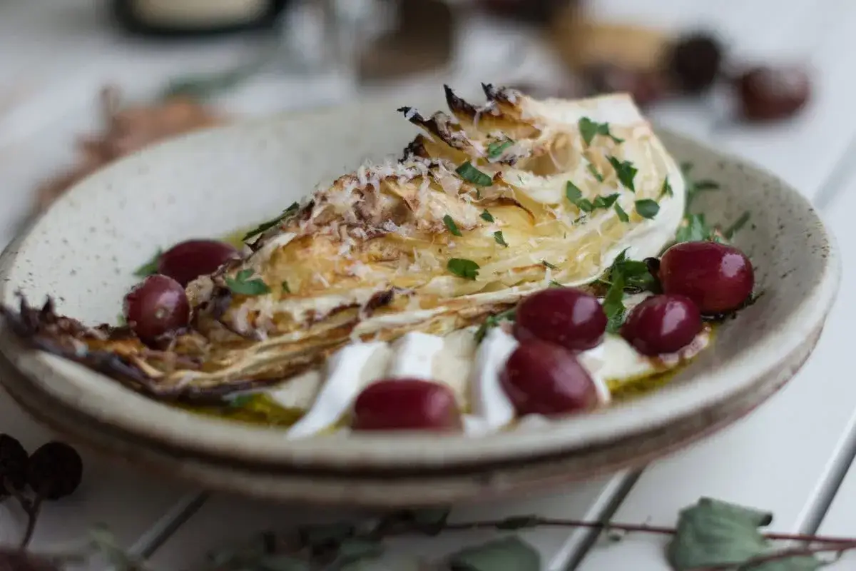 Gerösteter Schmorkohl als Beilage mit Hummus, Trauben und Käse.