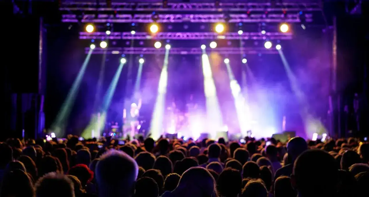 Menschenmenge bei einem **Sea Dance Festival** im Scheinwerferlicht. Lichter tanzen &uuml;ber die jubelnde Menge.