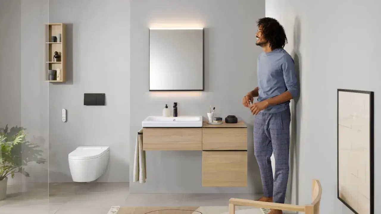 Modern badrum med en stilren vägghängd toalett, liknande japanska toaletter, och en man i morgonrock.