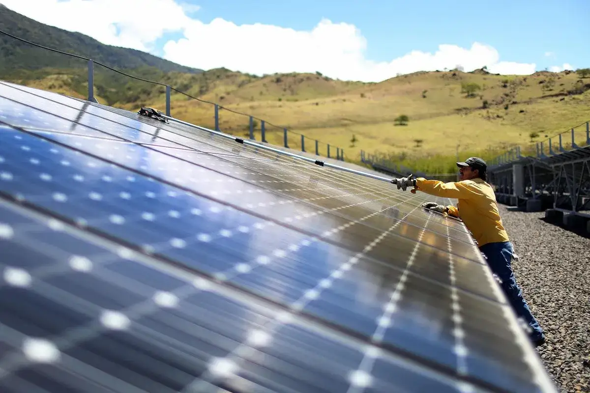 Mann reinigt Solarmodule in Costa Rica, ein Beispiel f&uuml;r erneuerbare Energien.