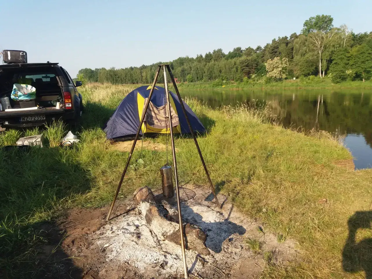Namiot i ognisko nad rzeką, gotowe na nocleg. Idealne miejsce na **nude camp** i relaks na łonie natury.