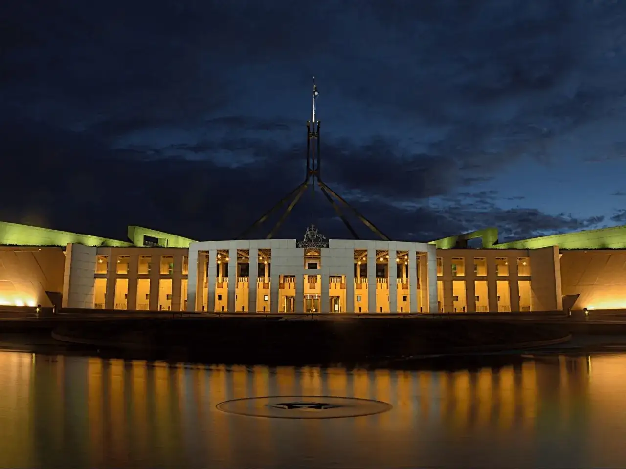 Parlament Australii nocą, z charakterystyczną wieżą i odbiciem w wodzie. To serce stolicy Australii, Canberry.