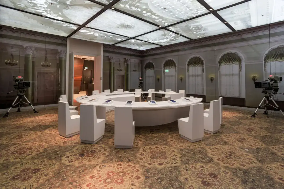 Sala obrad w Muzeum Solidarności w Gdańsku, z okrągłym stołem i krzesłami, kamery filmowe.