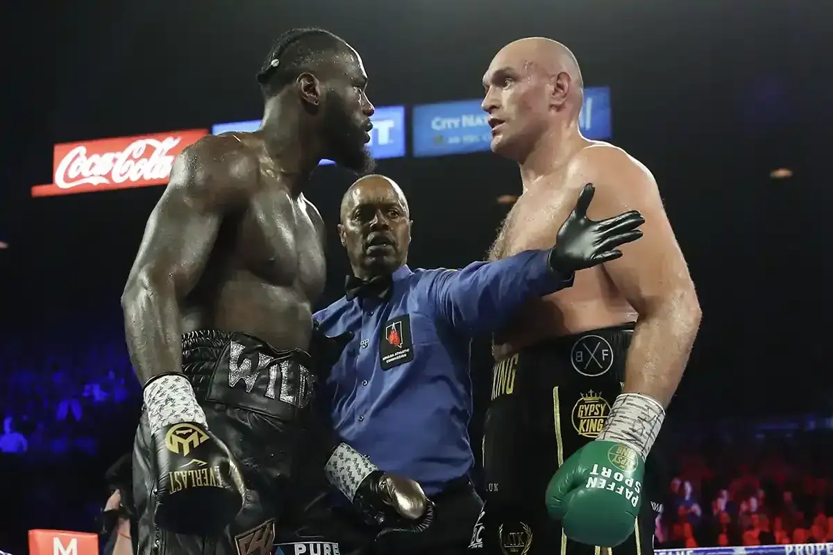 Two heavyweight boxers, Deontay Wilder and Tyson Fury, face off as a referee separates them. This is not what weight is middleweight.