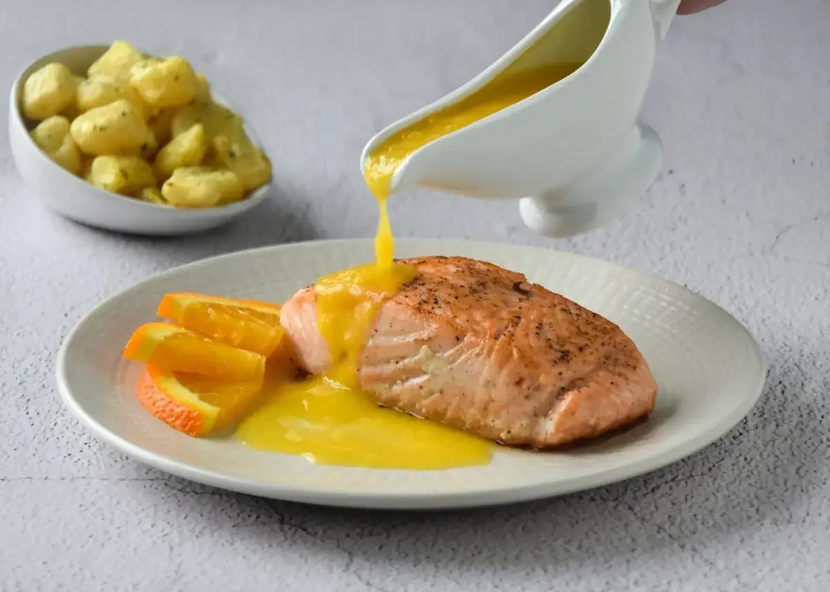Filete de salmón a la naranja, bañado en salsa cítrica, acompañado de gajos de naranja y patatas.