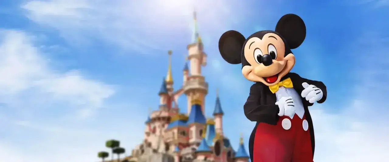 Myszka Miki wita przed zamkiem. Sprawdź aktualną disneyland cena biletu i zaplanuj magiczną podróż!