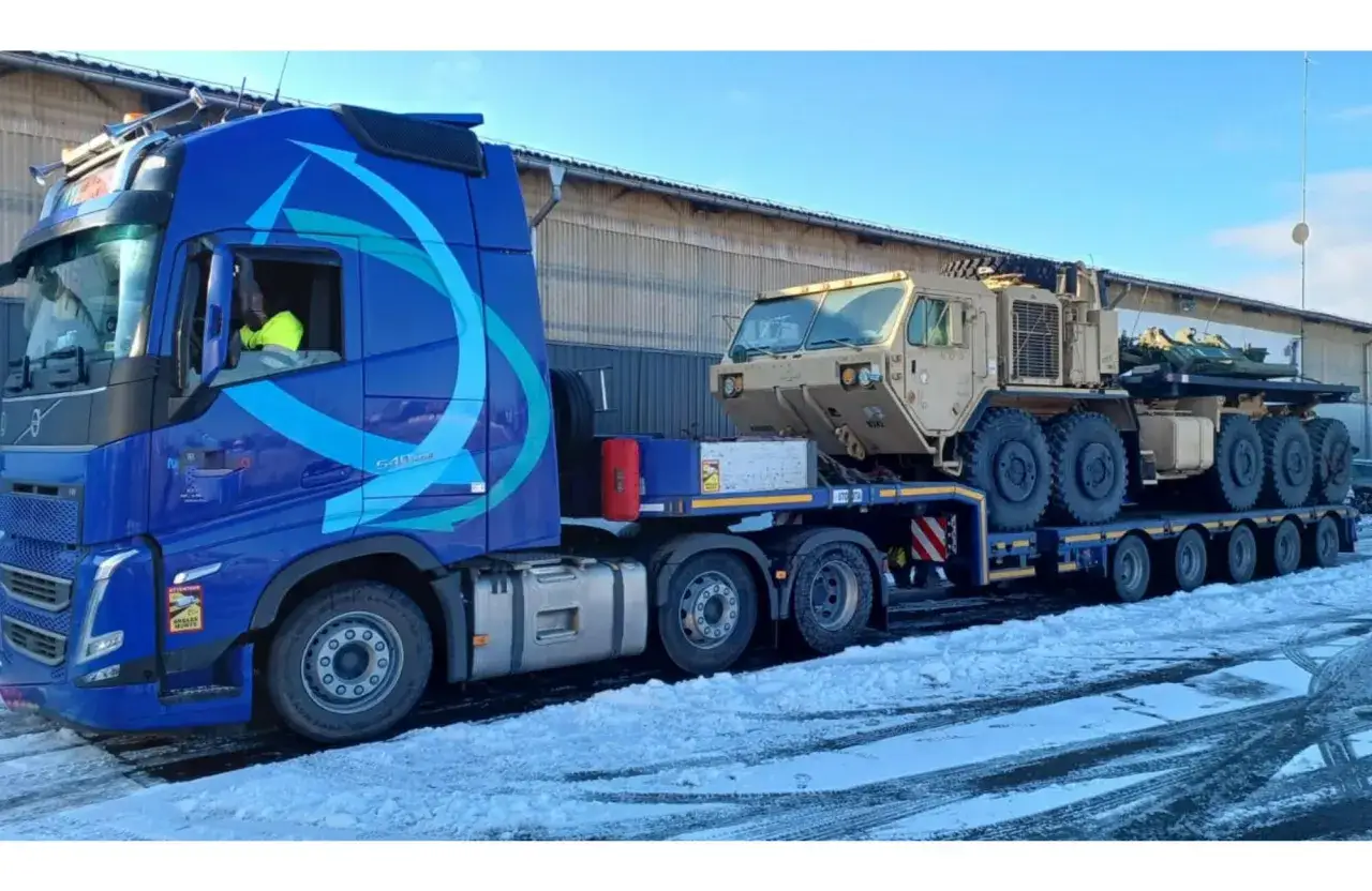 Blauer Volvo-LKW transportiert schweres Milit&auml;rfahrzeug. Das **Tara Gewicht** des Transports ist betr&auml;chtlich.