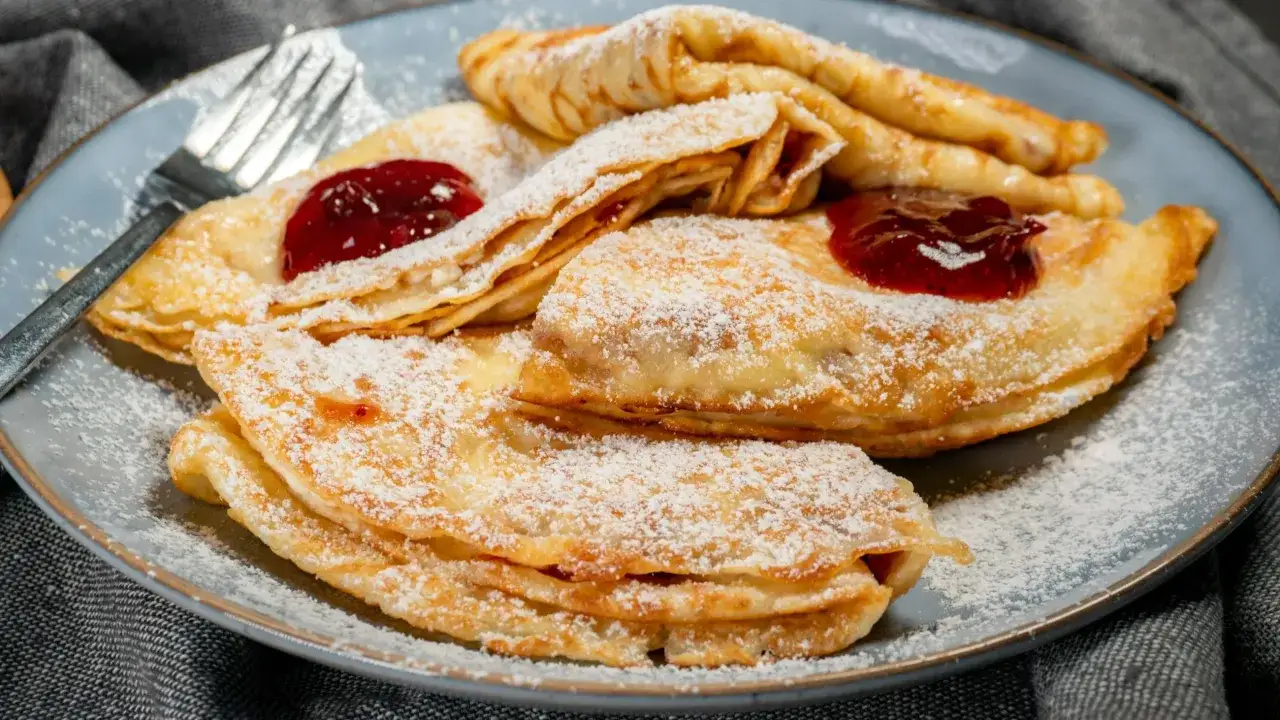 Naleśniki z serem ricotta i dżemem, posypane cukrem pudrem. Idealne na deser lub śniadanie.