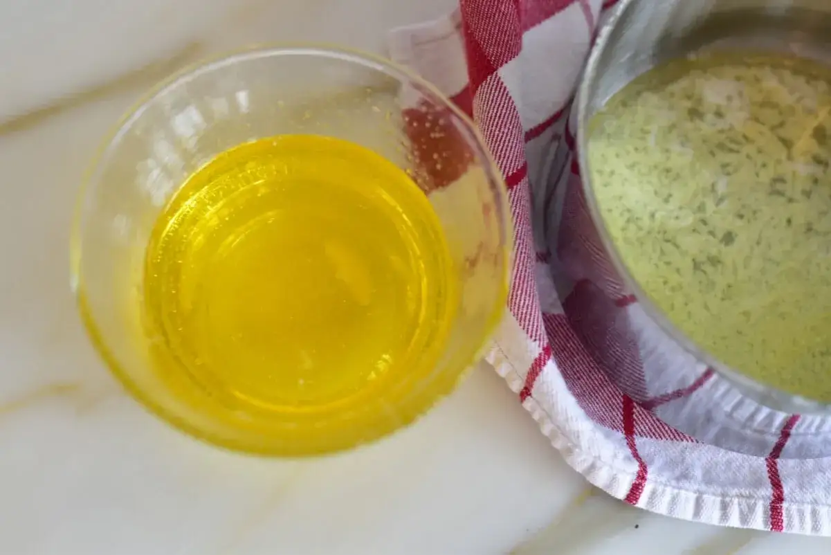 Ghee, ett gyllene, klarat smör, i en skål bredvid en kastrull med smält smör.