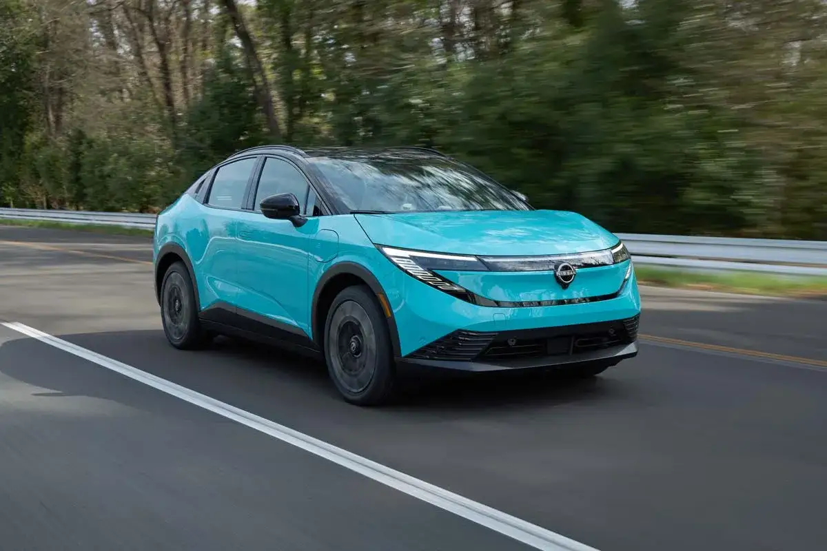 En turkos Nissan Leaf 2026 glider fram p&aring; en v&auml;g, med tr&auml;d som suddas ut i bakgrunden.