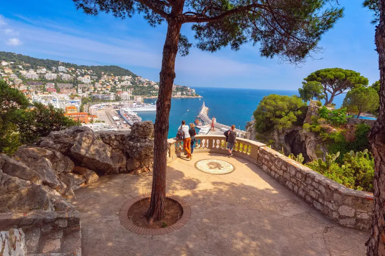 Vue panoramique sur le port de Nice, avec des bateaux de croisi&egrave;re. Un couple profite d'un week end nice sur la terrasse.