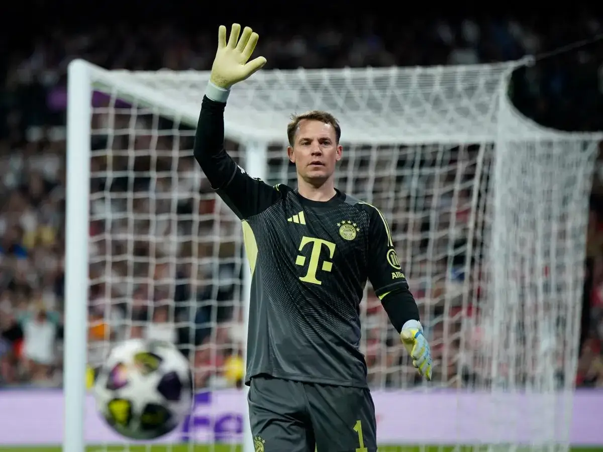 Manuel Neuer, bramkarz Bayernu, w akcji. Wznosi rękę na powitanie kibiców, gotowy do obrony bramki.