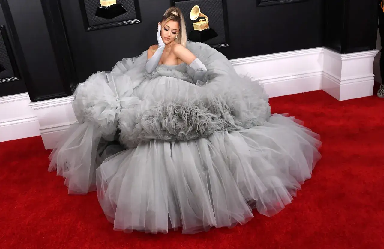 Ariana Grande w szarej, tiulowej sukni na czerwonym dywanie. Mimo choroby, gwiazda prezentuje się olśniewająco.