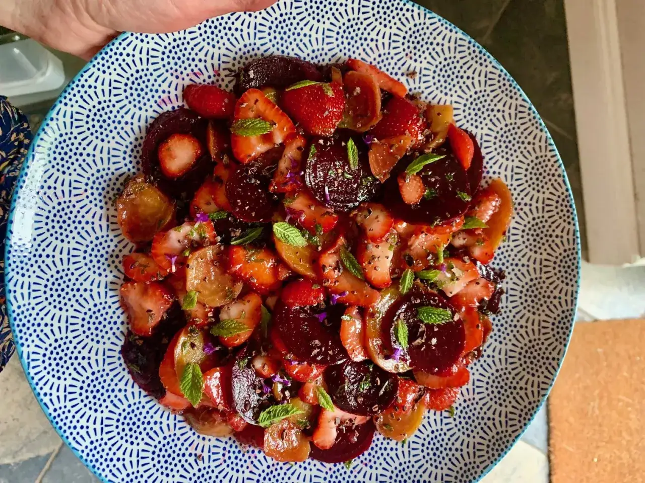 Bunte Carpaccio Variationen mit Erdbeeren, Roter Bete und Minze auf einem blau-wei&szlig;en Teller.