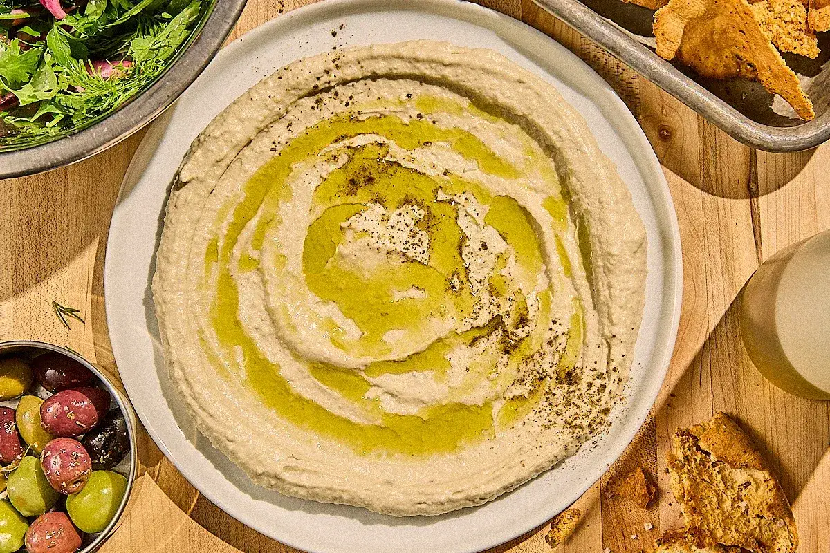 Kr&auml;mig hummus med olivolja och kryddor, perfekt f&ouml;r ditt n&auml;sta recept. Serveras med oliver och pitabr&ouml;d.