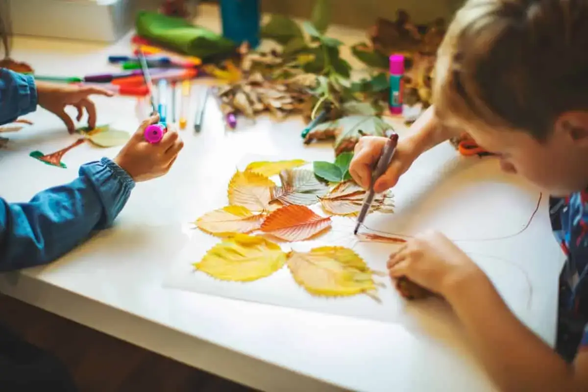 Ni&ntilde;os de oto&ntilde;o creando arte con hojas secas y rotuladores.