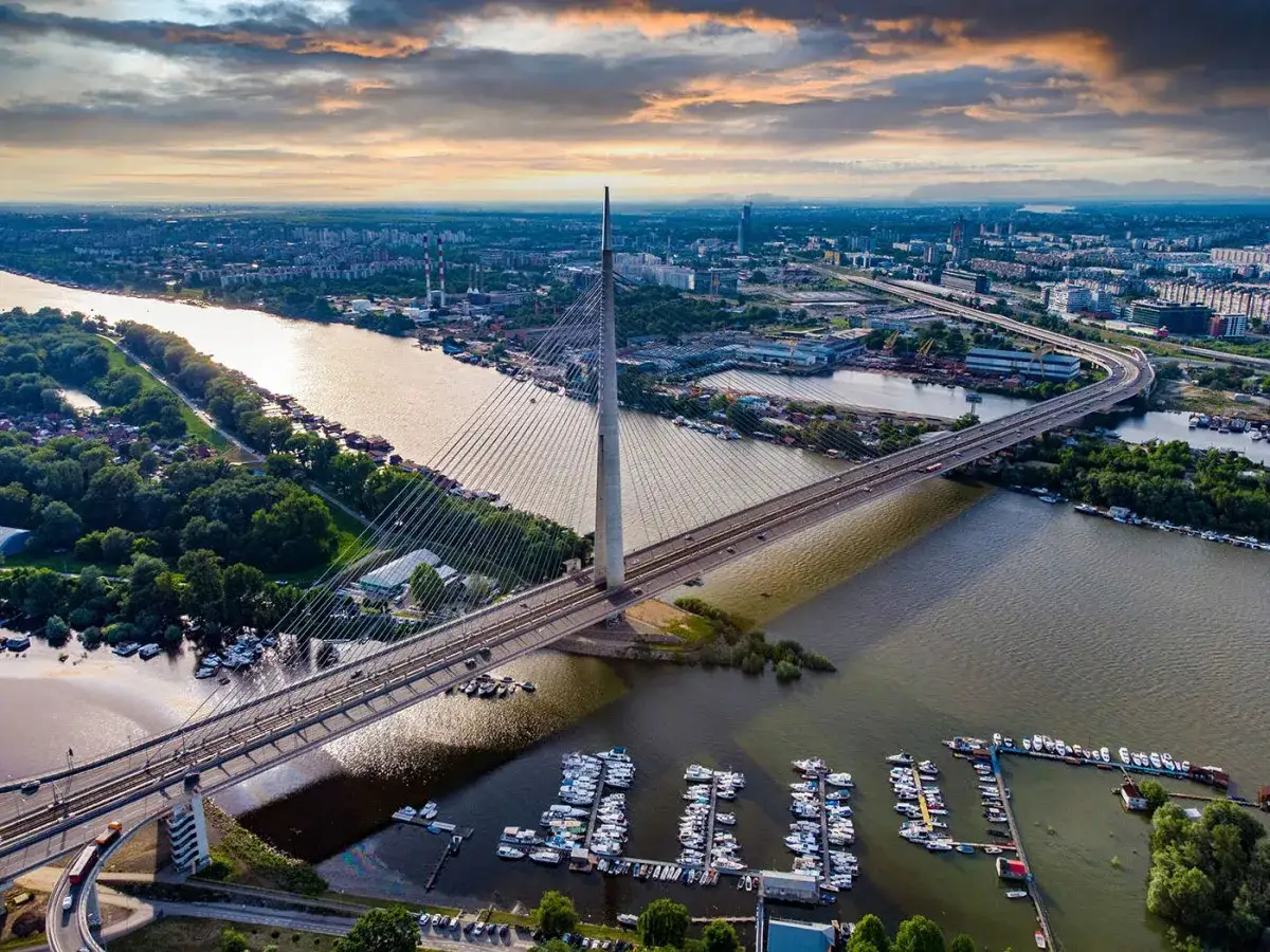 Most nowoczesnego miasta nad rzeką, z łodziami w porcie. Widok zachęca do podróży i zastanowienia: czy w Serbii jest bezpiecznie?