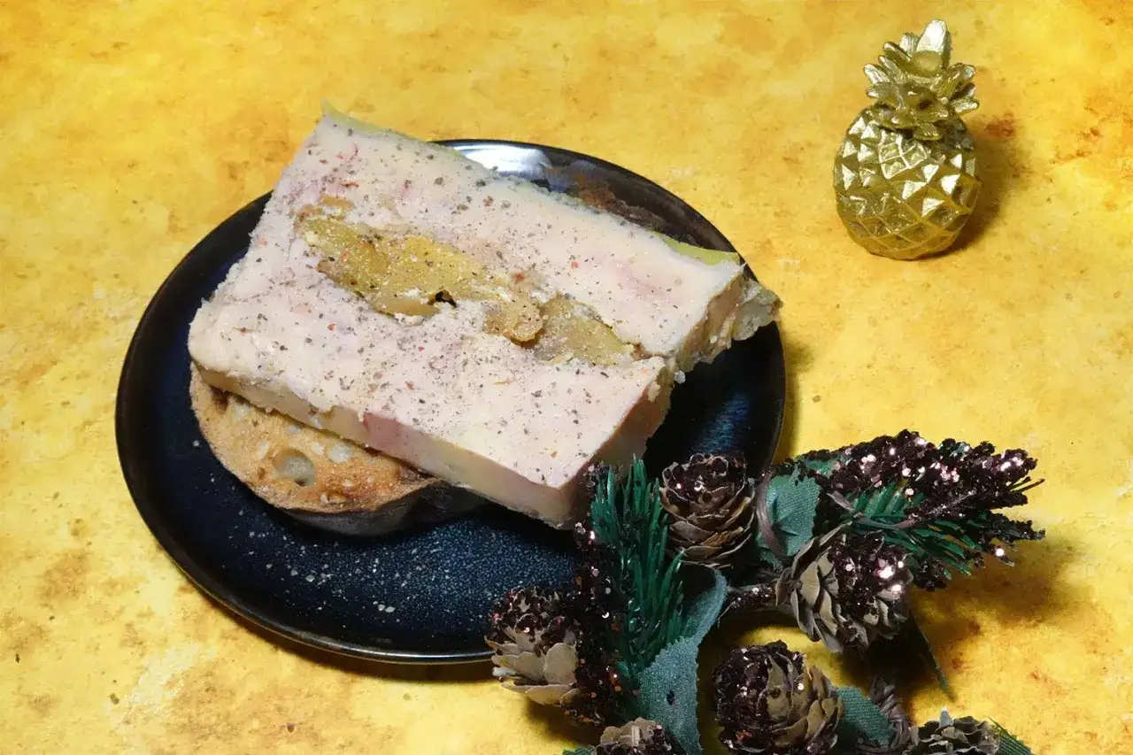Tranche de foie gras sur pain grill&eacute;, parsem&eacute;e de poivre. Une touche de rhum pour sublimer ce d&eacute;lice. D&eacute;coration festive avec des pommes de pin paillet&eacute;es.