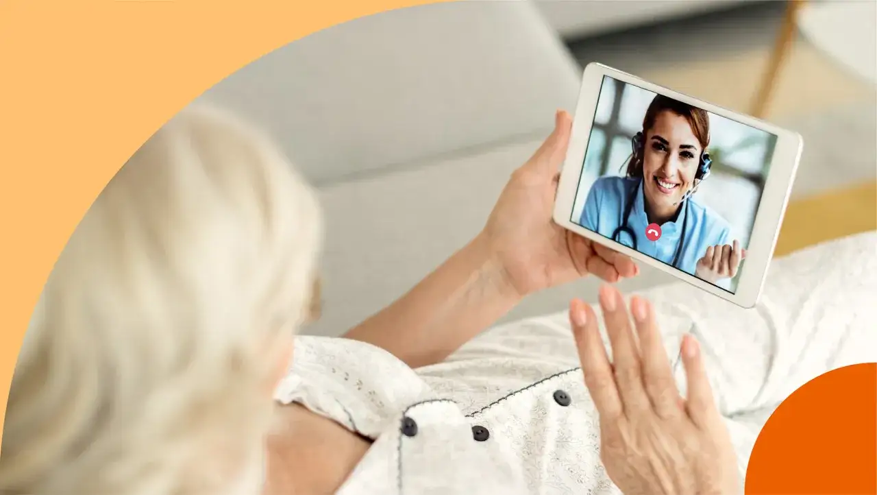 Ältere Frau hält Tablet mit Arzt im Videoanruf. Sie winkt, fühlt sich unsicher, aber die Ärztin lächelt beruhigend.