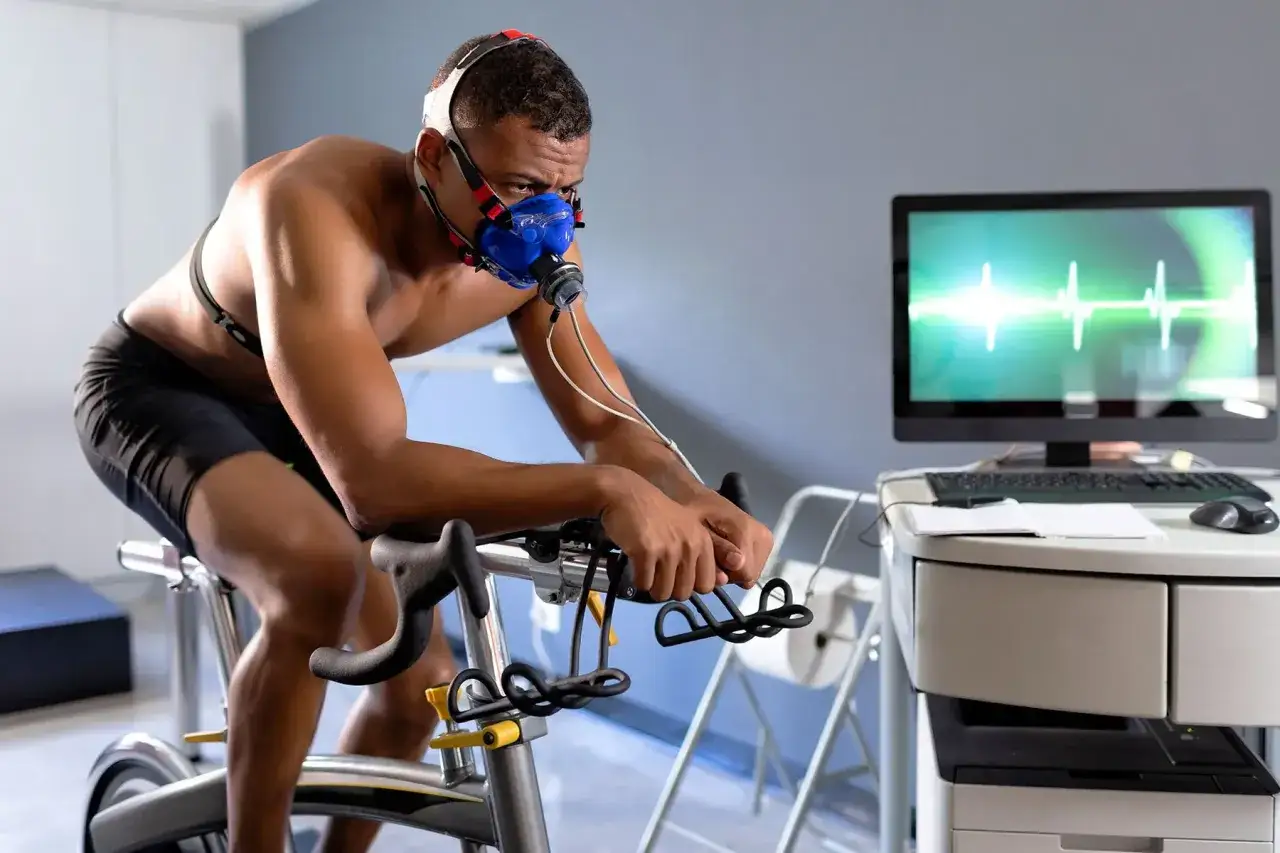 Athlete undergoes a VO2 max test, similar to what Jonas Vingegaard might do, on a stationary bike with a mask and monitor.