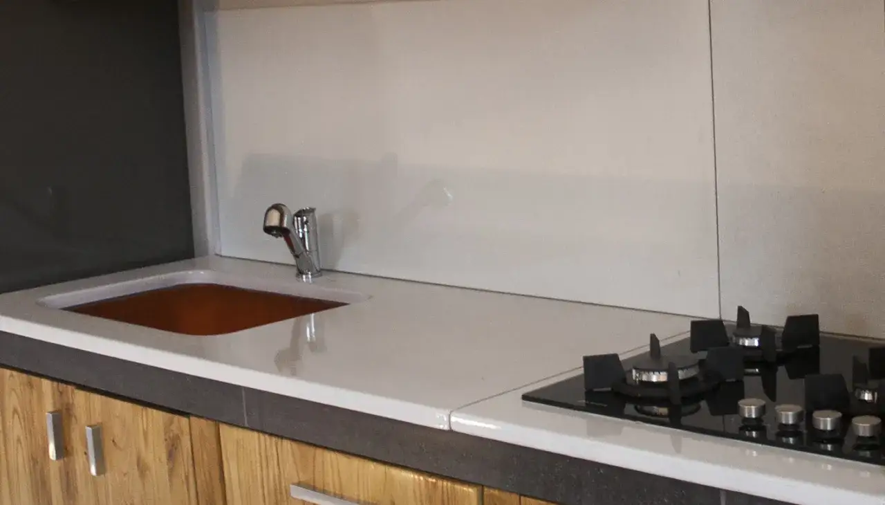 Top cucina in pietra lavica: pro e contro. Un piano di lavoro moderno con lavello in rame e piano cottura a gas.