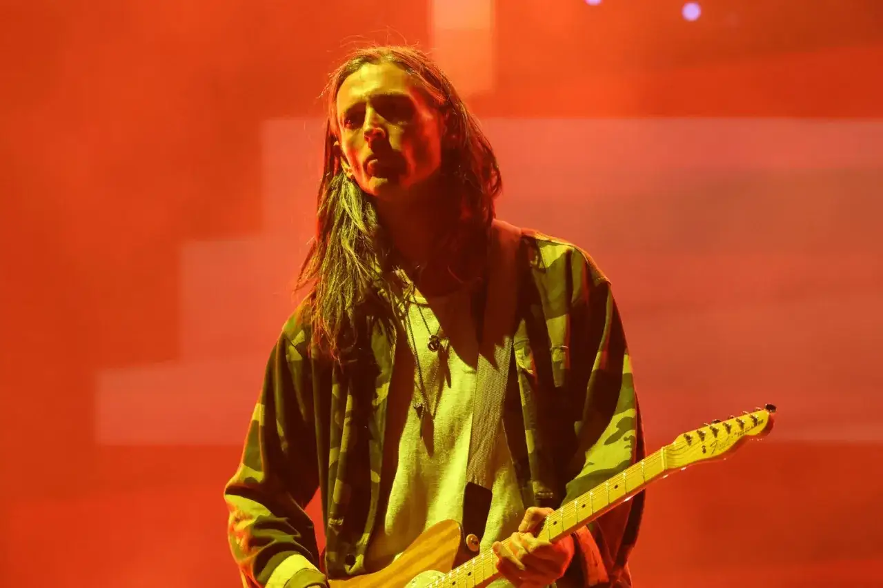 Nick Valensi spielt Gitarre auf einer B&uuml;hne im Scheinwerferlicht.