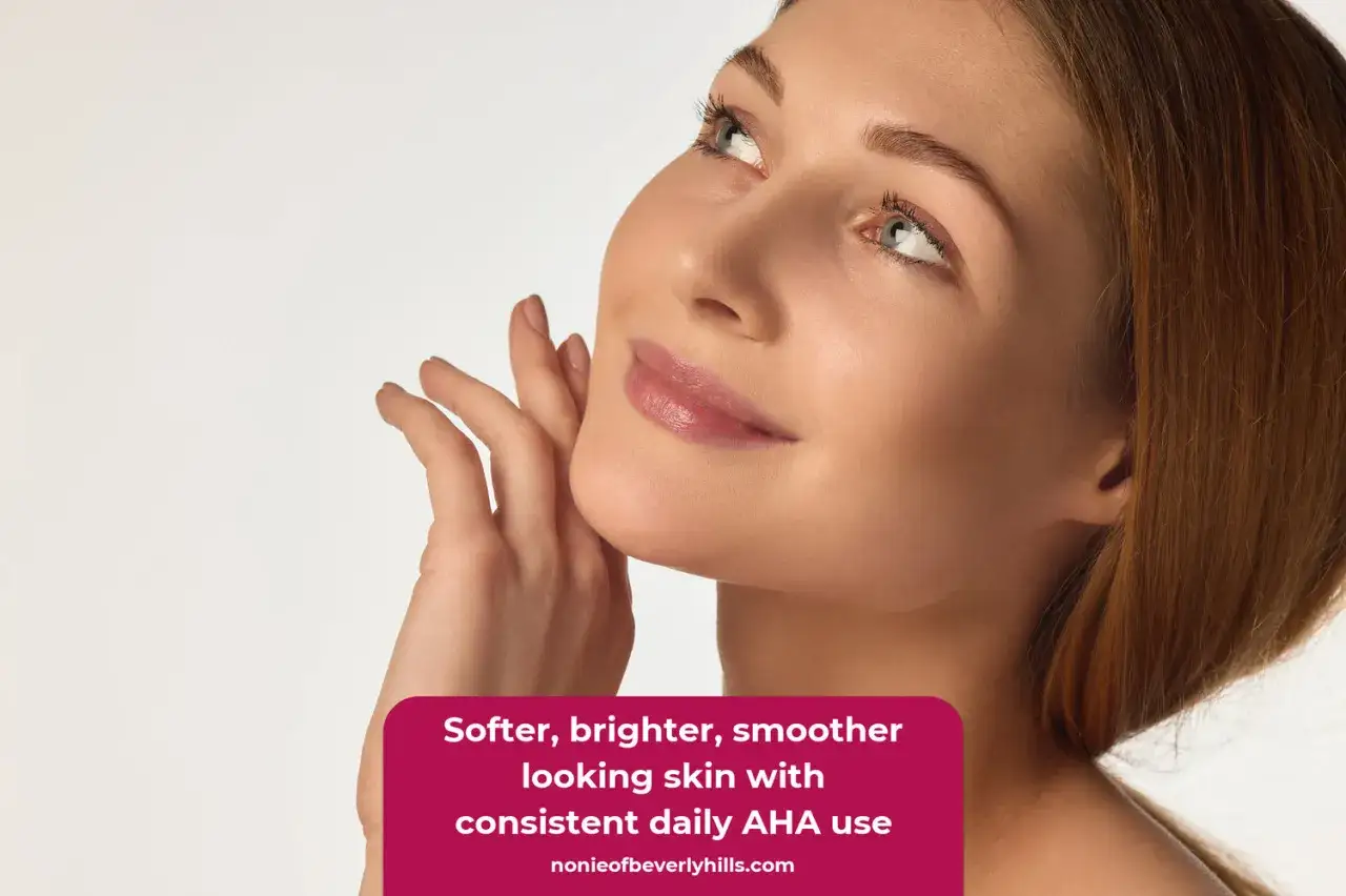 Une femme caresse son visage, sa peau est douce et lumineuse gr&acirc;ce &agrave; l'usage quotidien d'AHA.