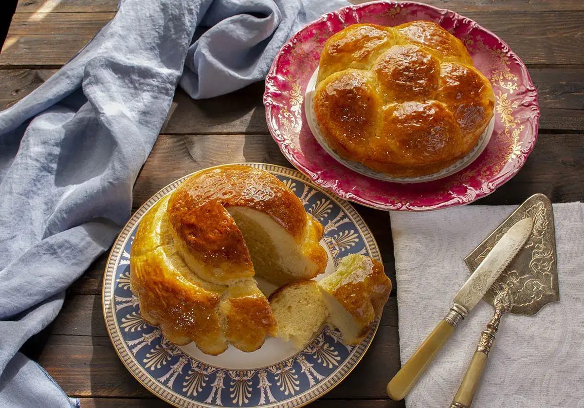Dos panes brioche dorados y glaseados, uno cortado, listos para disfrutar. Una delicia para tu próxima receta brioche.